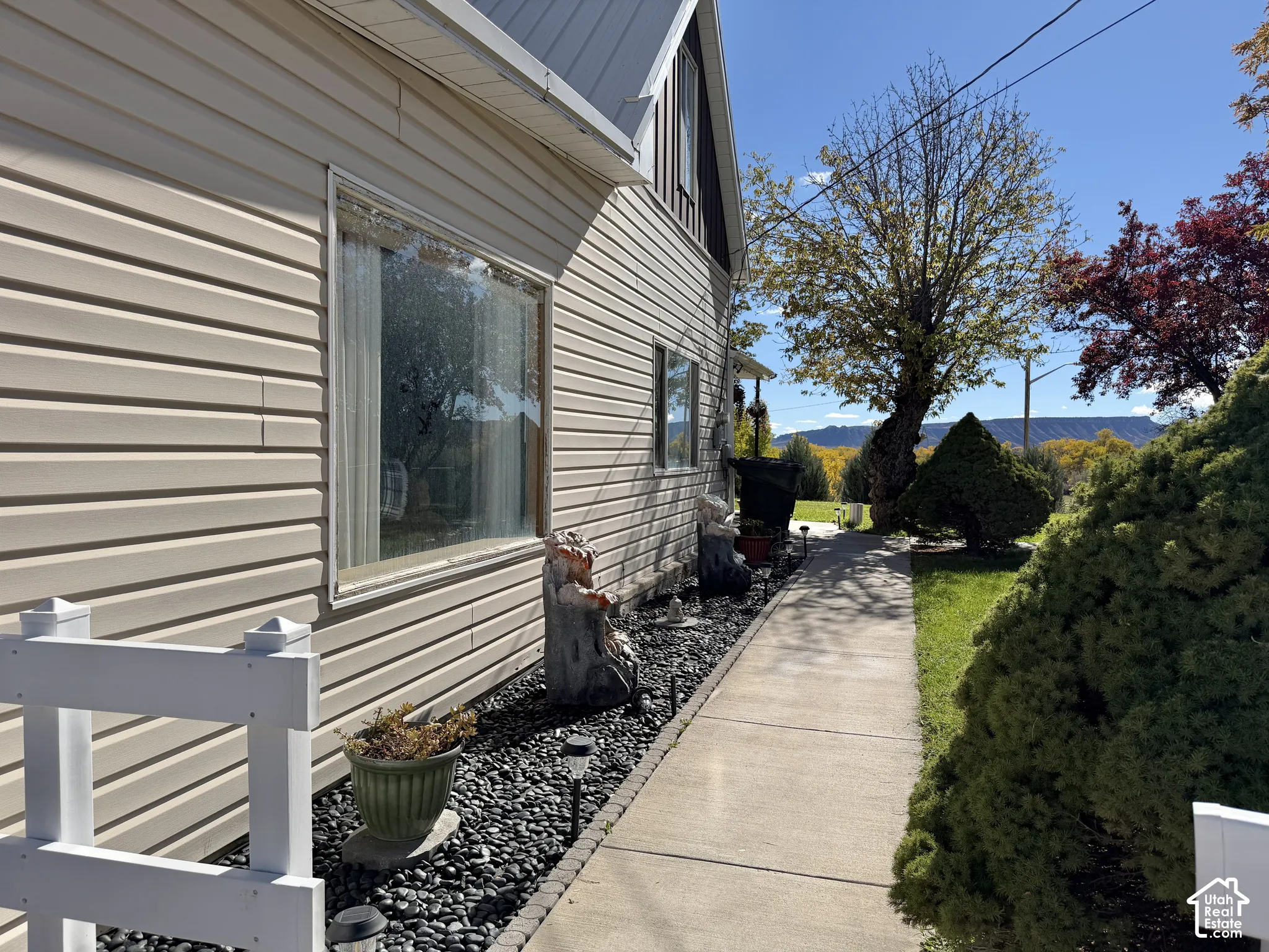 Horizontal siding exterior with a metal roof, concrete walkway, and black stone landscaping bed
