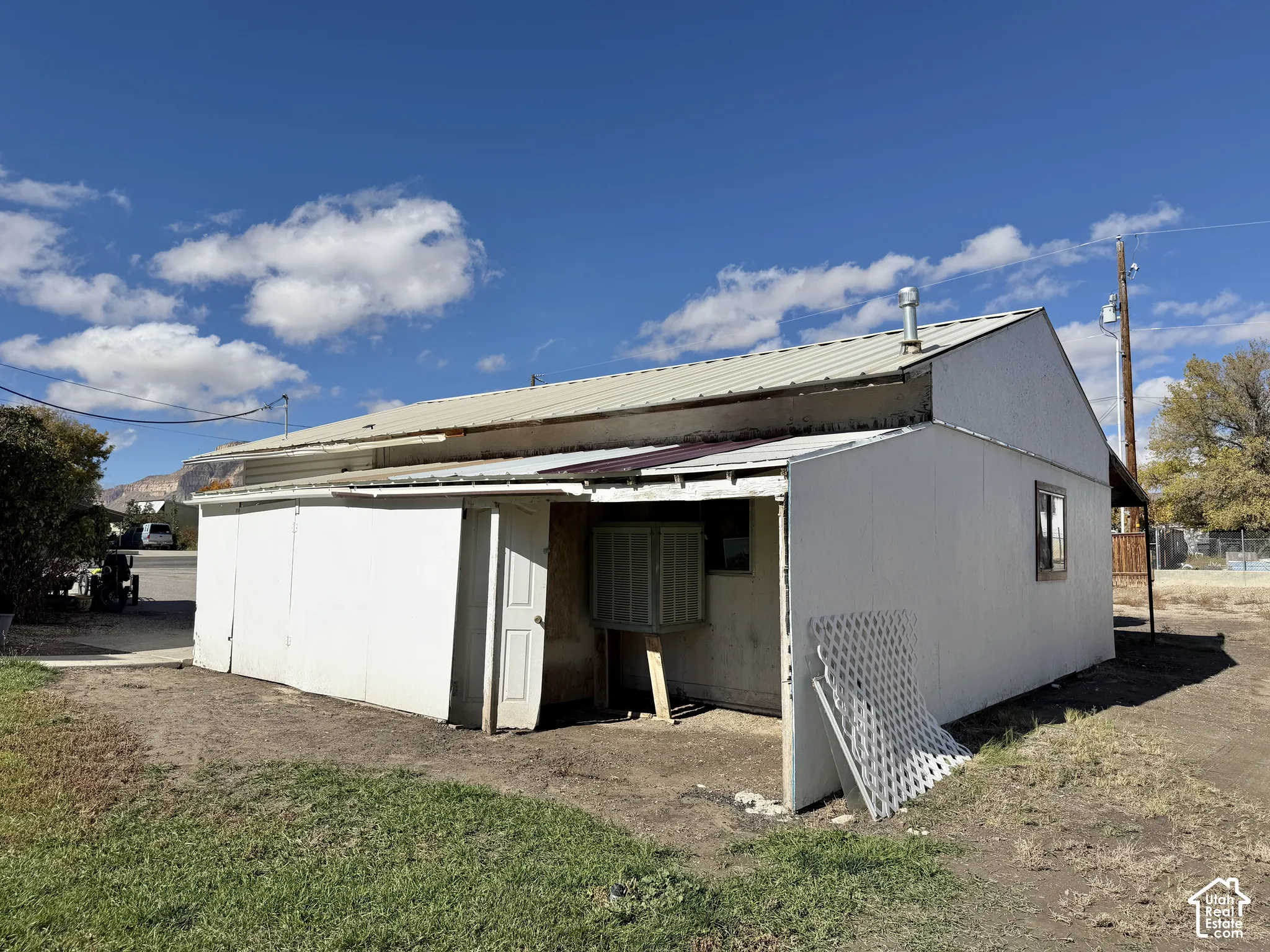 Single-story structure featuring a metal roof, white siding, and an evaporative cooling unit