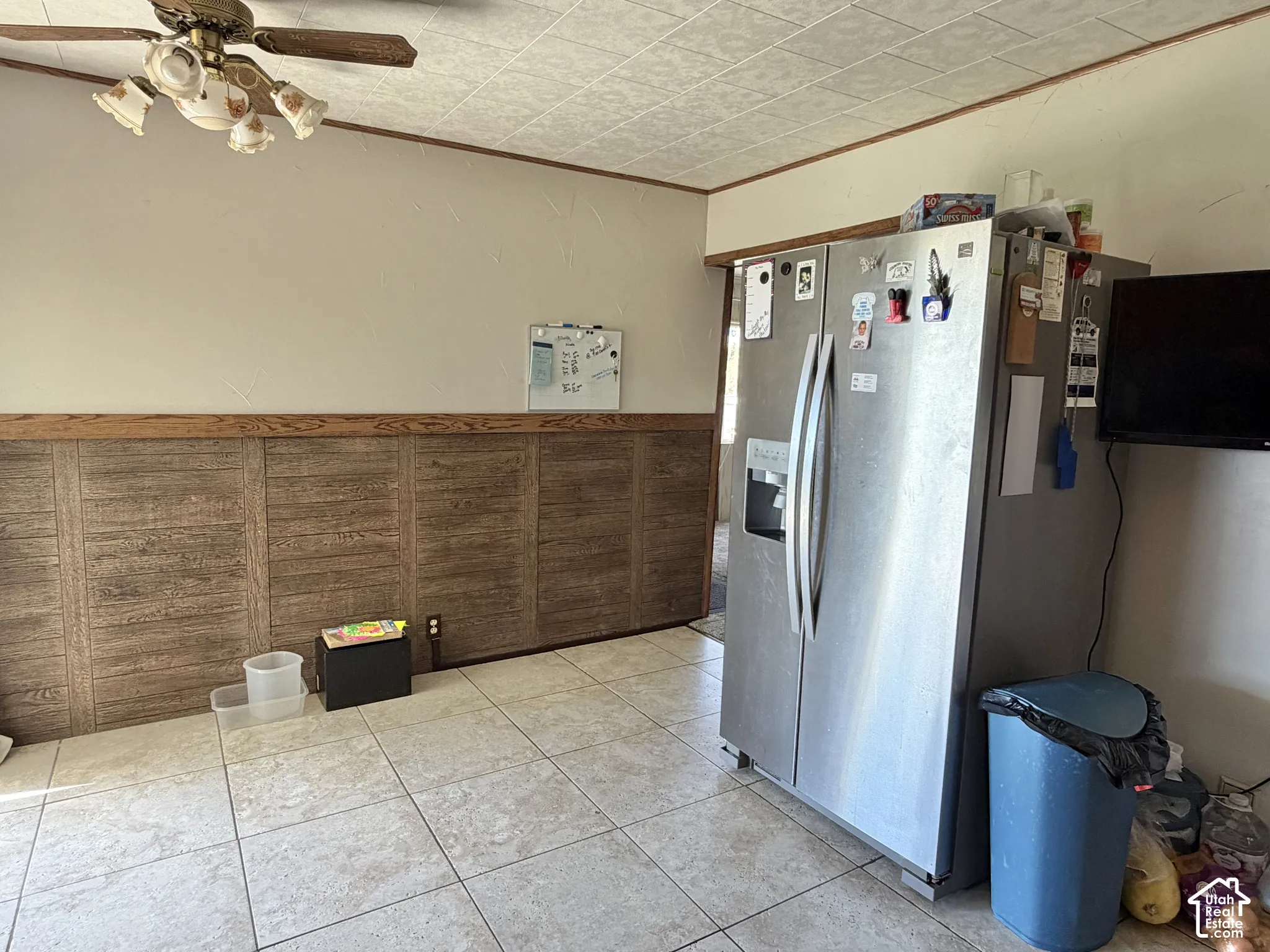 Ceramic tile flooring, paneled wainscoting with wood trim, and stainless steel side-by-side refrigerator