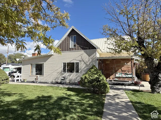 Exterior featuring horizontal siding, natural stone accents, a metal roof, and a paved walkway