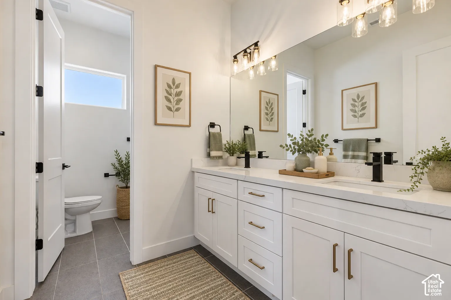 Dual-sink vanity with white shaker-style cabinetry, stone-composite countertop, matte black fixtures, and large frameless mirror