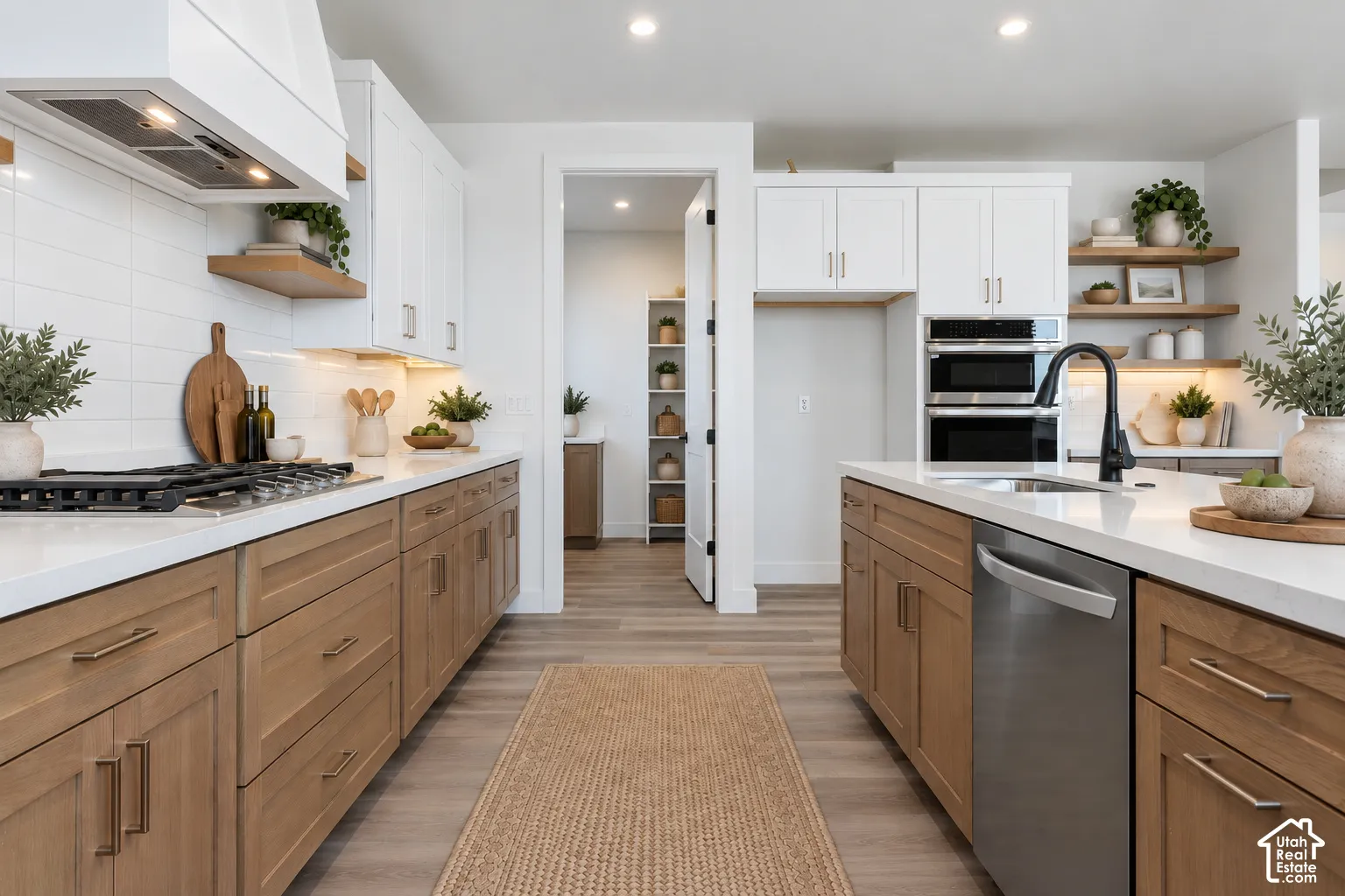 Kitchen featuring dual-tone cabinetry, quartz countertops, subway tile backsplash, built-in double wall oven, and wood-finish flooring