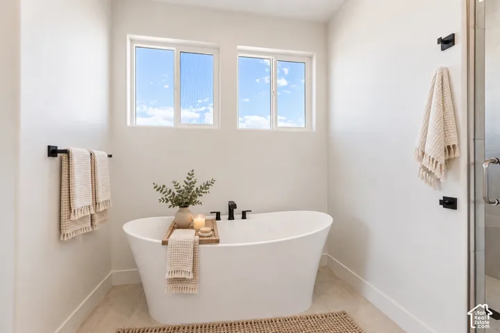 Freestanding soaking tub with matte black deck-mounted faucet, dual windows, and matte black hardware