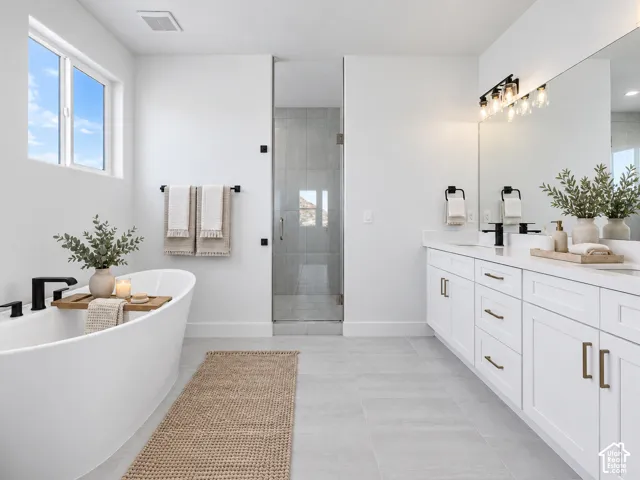 Freestanding soaking tub with matte black fixtures, white shaker-style dual vanity with solid surface countertops, expansive wall-to-wall mirror, and glass-enclosed shower with tile surround
