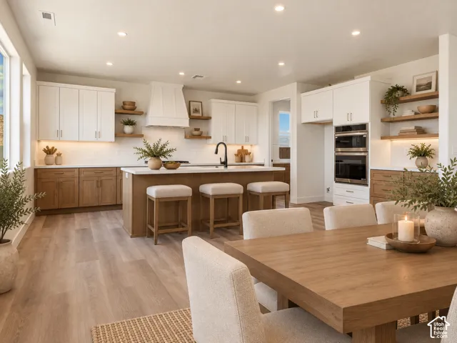 Kitchen featuring dual-tone cabinetry, wood-finish flooring, a central island with a solid surface countertop, built-in double wall ovens, and open shelving