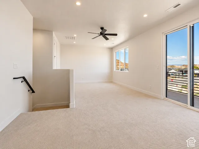 Open-concept area featuring neutral carpeting, recessed lighting, a matte black ceiling fan, and sliding glass doors with access to a balcony