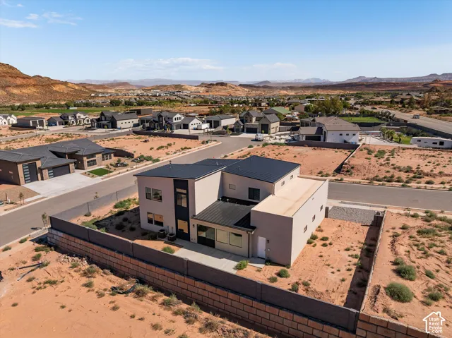 Contemporary two-story exterior with a metal roof, stucco finish, large glass window panels, and a concrete rear patio enclosed by a perimeter block wall