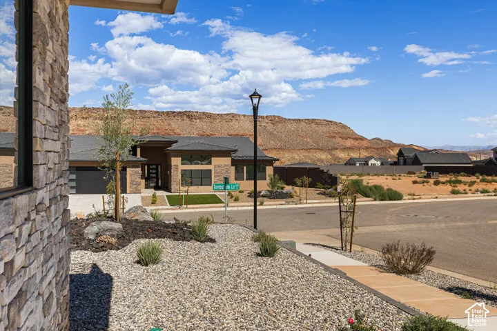 Exterior facade featuring stone veneer masonry, desert-inspired xeriscaping, and a prominent mesa backdrop