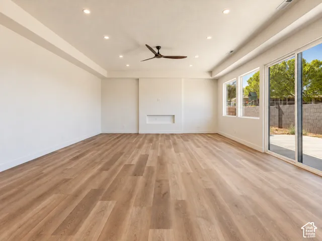 Spacious living area featuring wood-finish flooring, recessed lighting, a ceiling fan, a built-in fireplace niche, and sliding glass doors