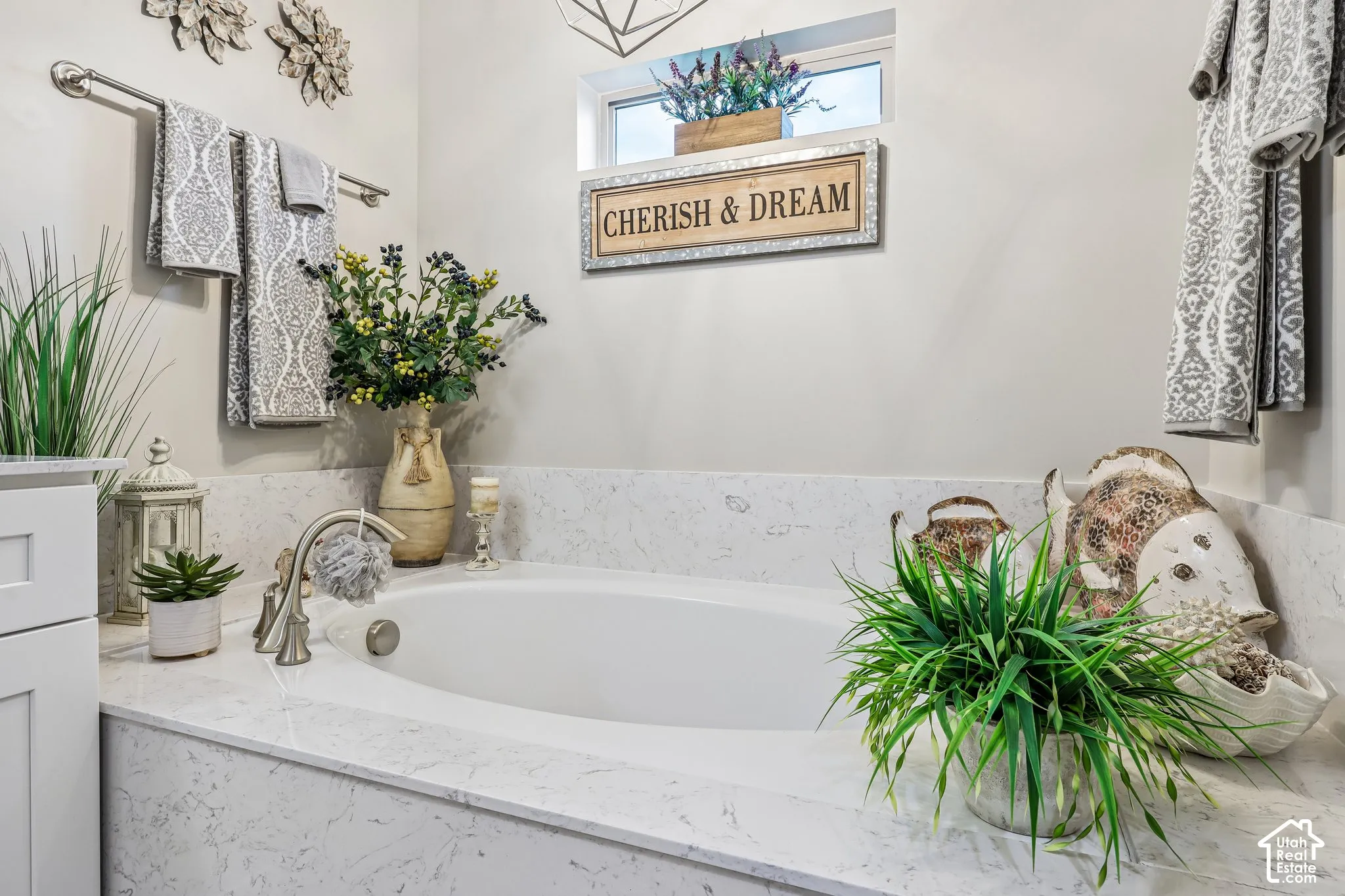 Built-in soaking tub with a stone-surround deck, polished metal faucet hardware, and a high-set clerestory window