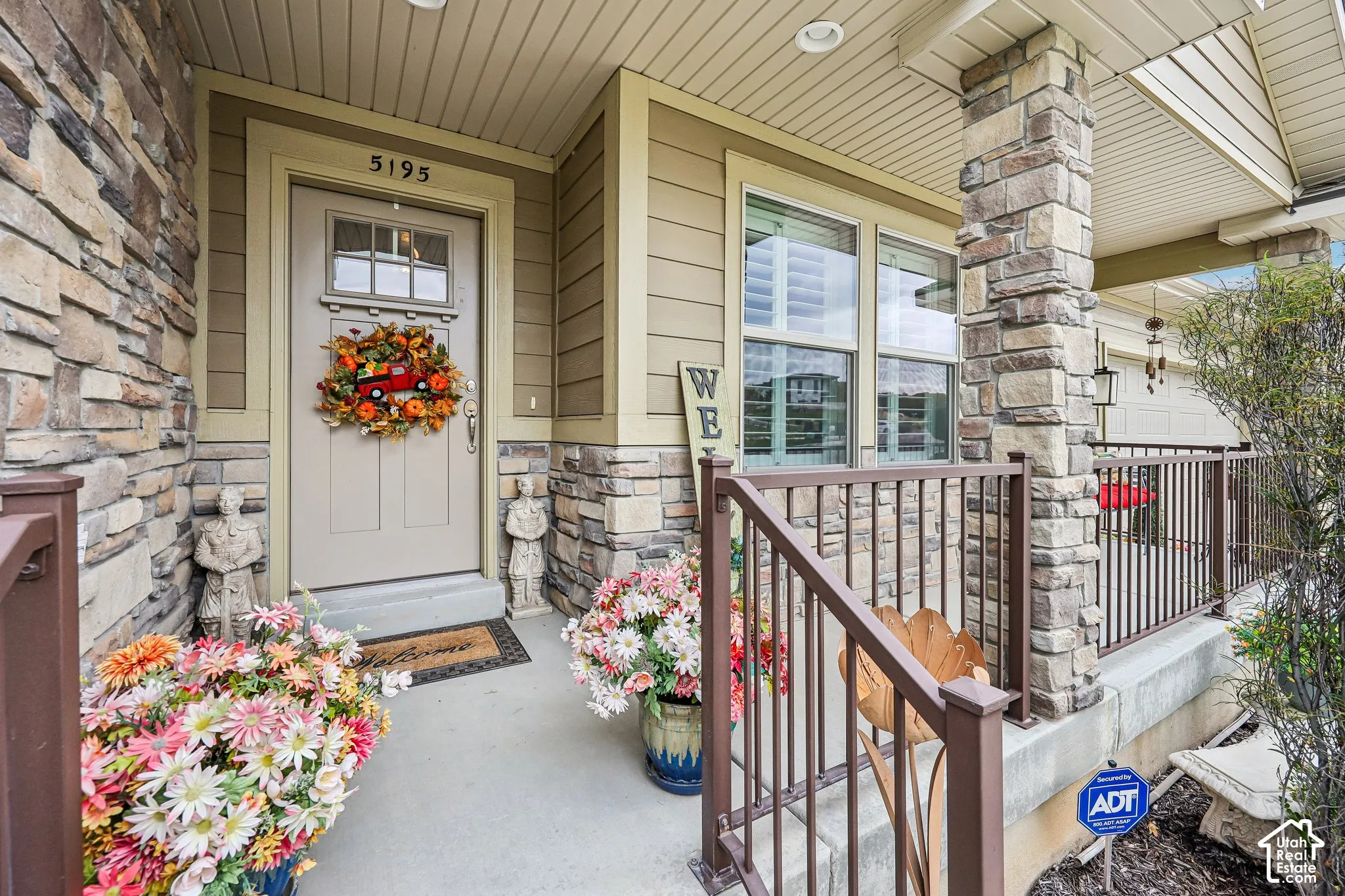 Covered entryway featuring natural stone veneer accents, multi-pane glass insert entry door, and metal railing