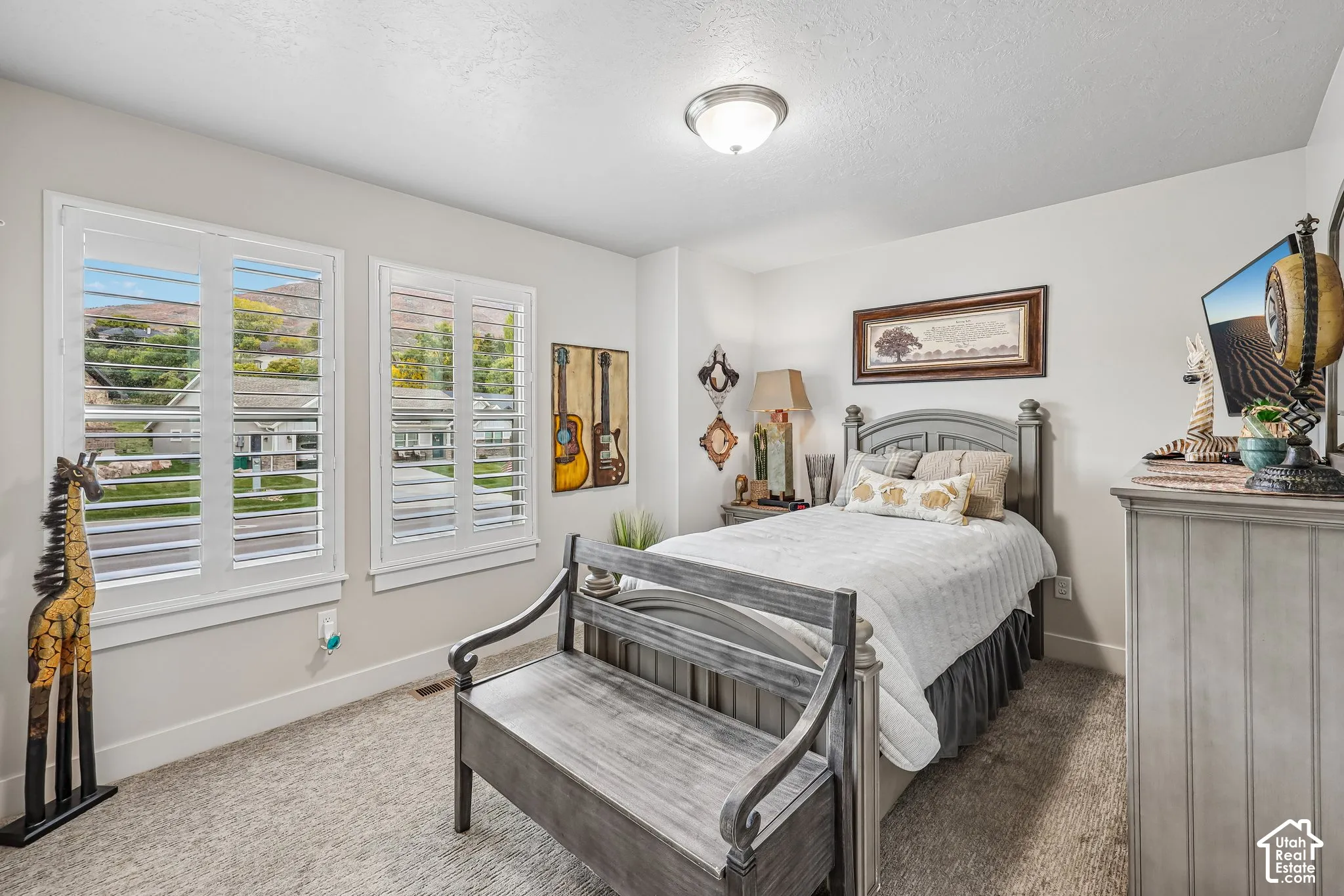 Interior room featuring neutral wall paint, plush carpeting, dual windows with white plantation shutters, and a central ceiling-mounted light fixture
