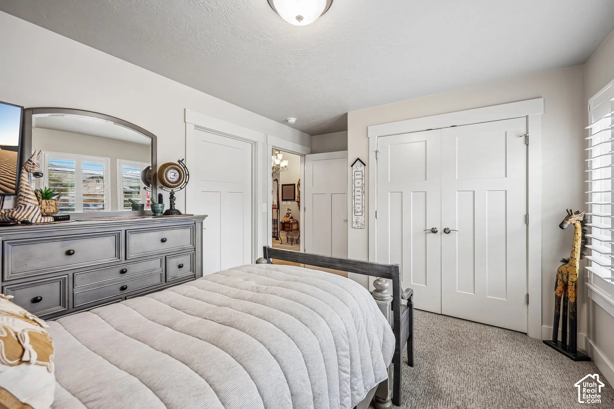 Room featuring neutral wall paint, carpeted flooring, white shaker-style interior doors, double-door closet, and white plantation-style shutters