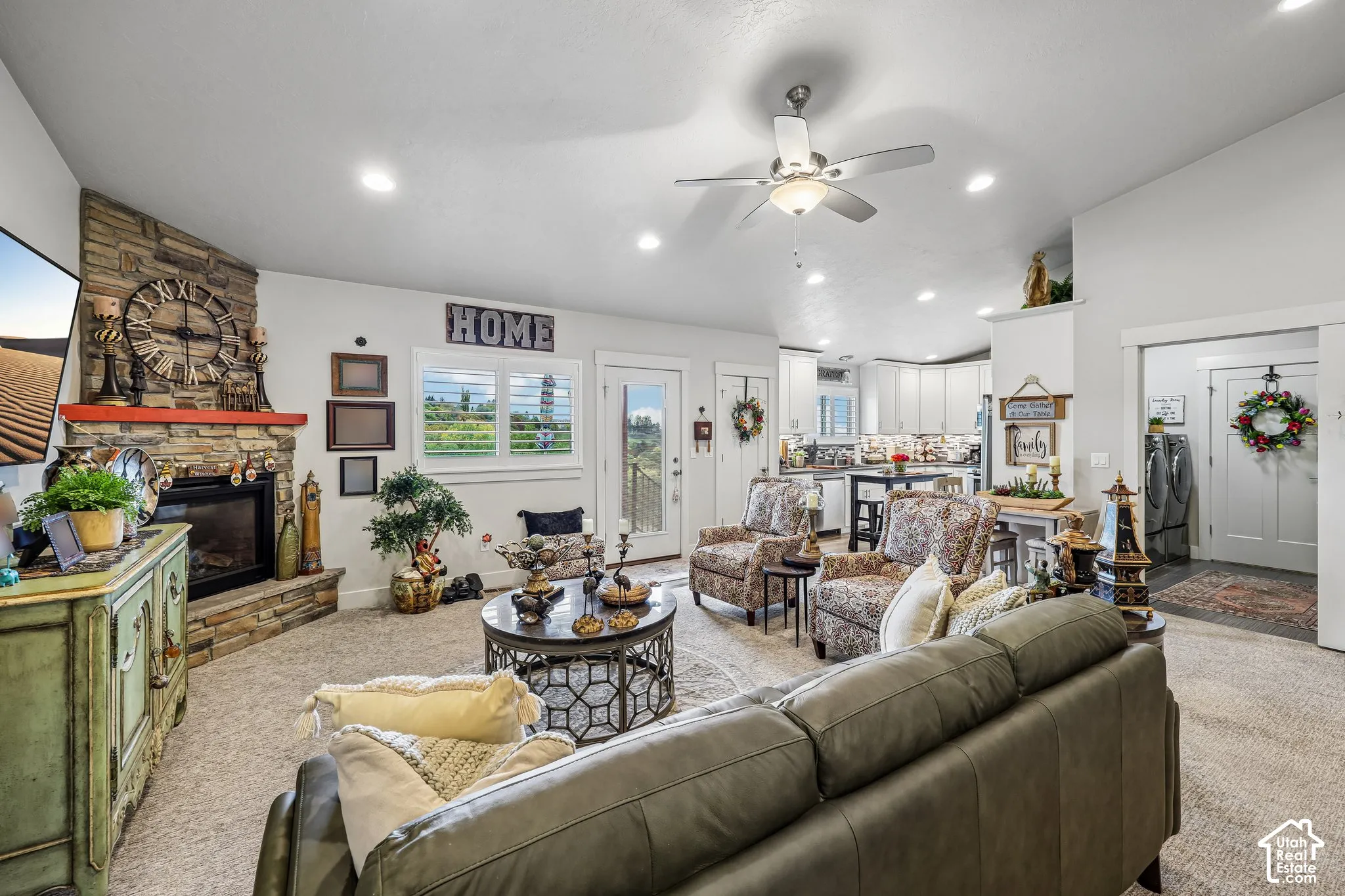 Living space featuring a corner stone-accented fireplace, vaulted ceilings with a center light fixture, recessed lighting, and plantation shutter window treatments