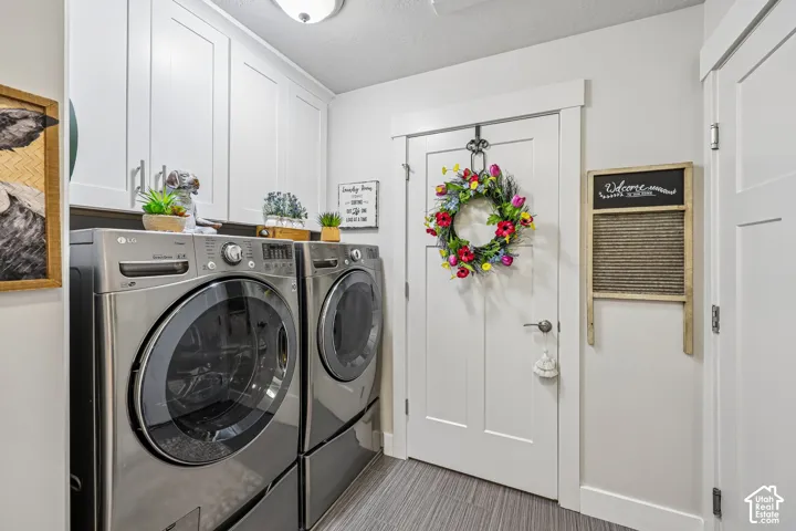 Laundry area featuring white Shaker-style upper cabinetry, stainless steel appliances, and multi-panel interior doors with wide trim casing