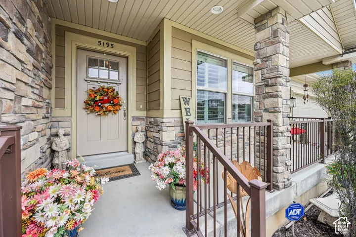 Covered entryway featuring natural stone veneer accents, multi-pane glass insert entry door, and metal railing