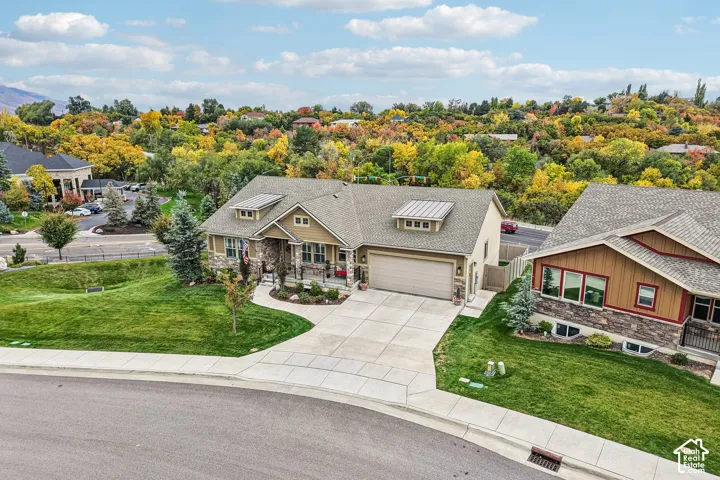 Exterior featuring a stone and siding facade, covered front entryway, shingled roofing with metal accents, attached multi-car garage, and concrete driveway
