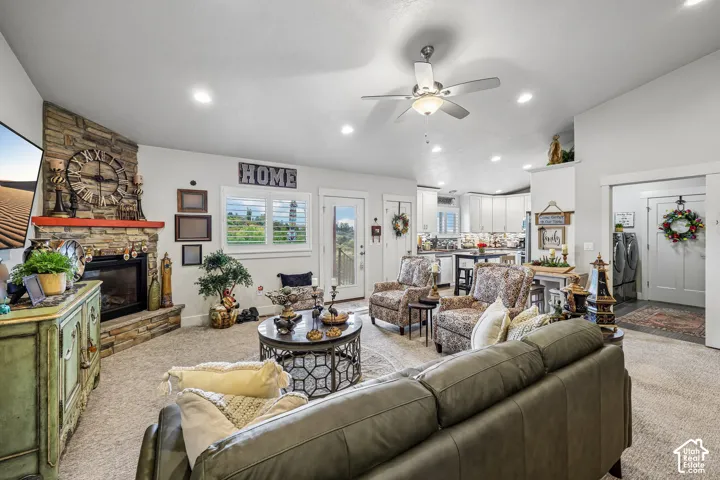 Living space featuring a corner stone-accented fireplace, vaulted ceilings with a center light fixture, recessed lighting, and plantation shutter window treatments