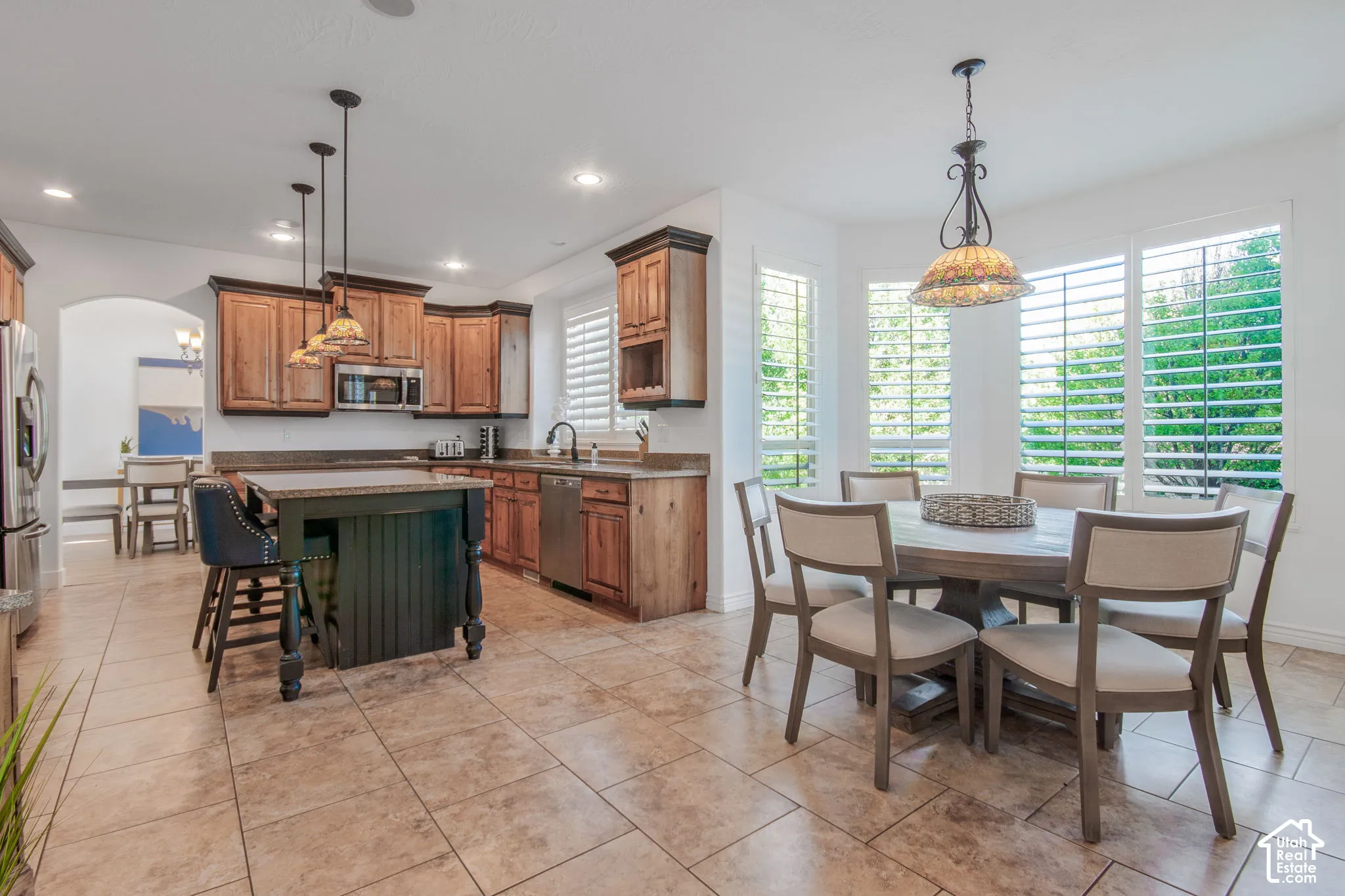 Kitchen featuring wood cabinetry, a center island with built-in seating, tile flooring, and windows with interior plantation shutters