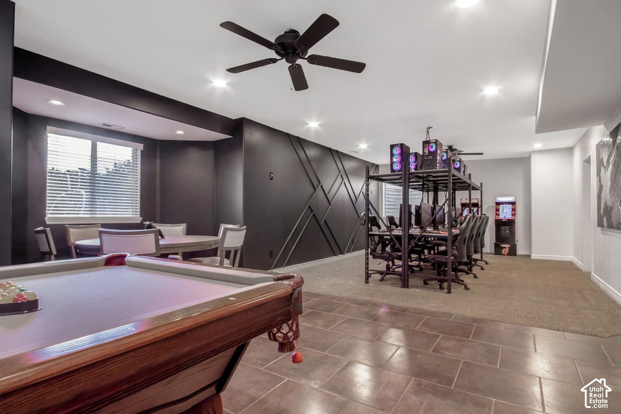 Recessed ceiling lighting, matte black ceiling fan, decorative wall paneling, tile flooring, and carpeted flooring