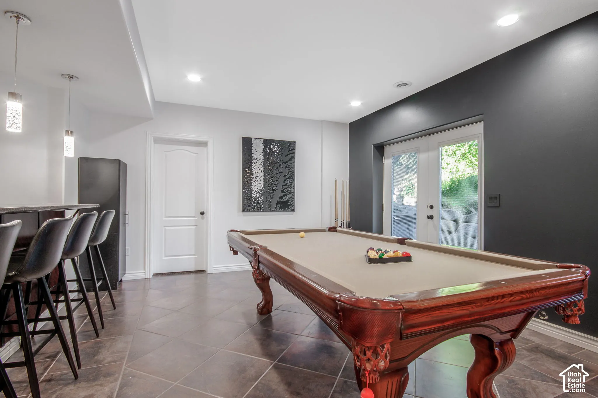 Built-in wet bar with pendant lighting, large-format tile flooring, dual-pane glass French doors, and recessed lighting