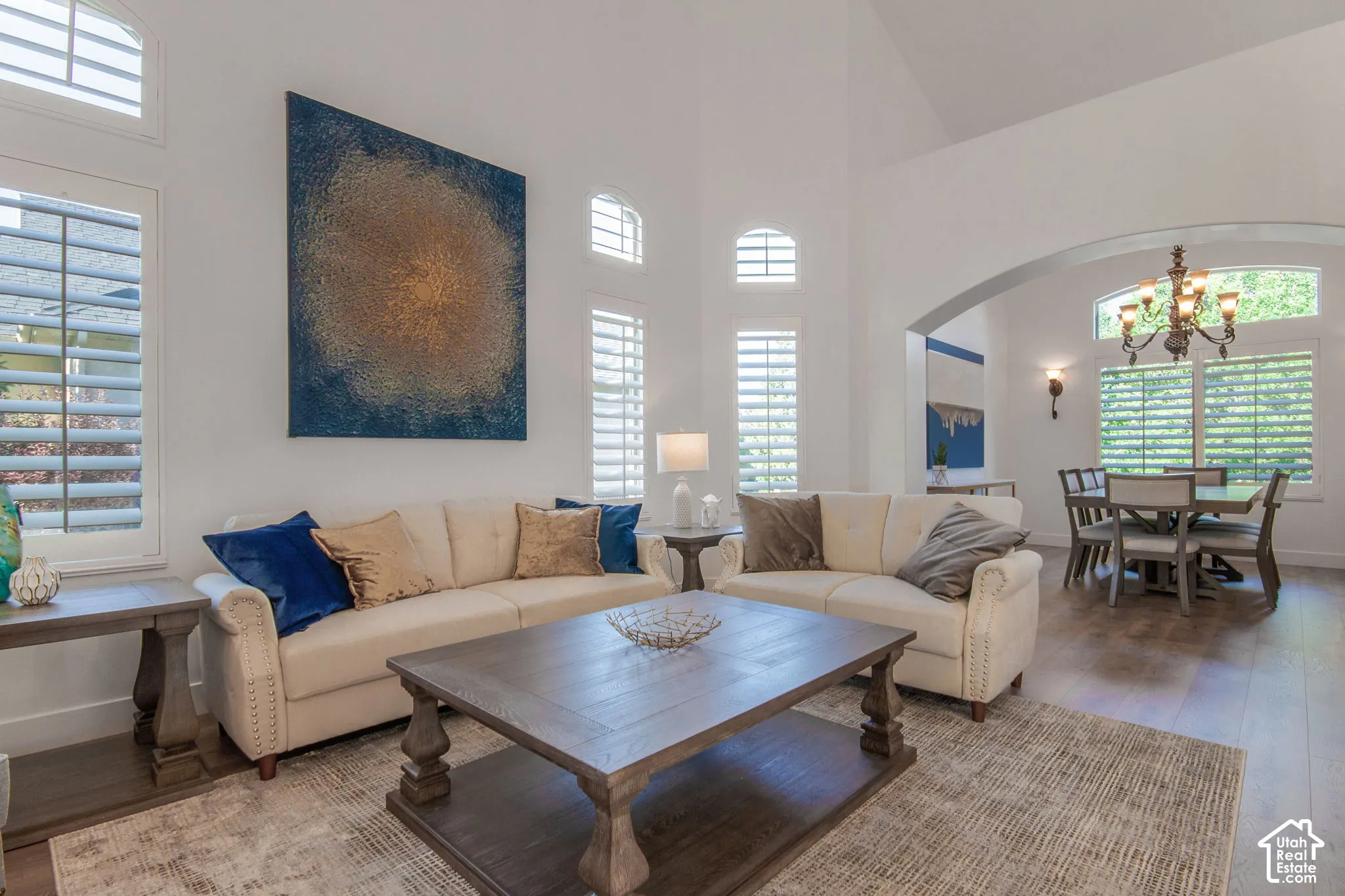 Vaulted ceilings, expansive windows with interior shutters, arched architectural entryways, and hard-surface flooring