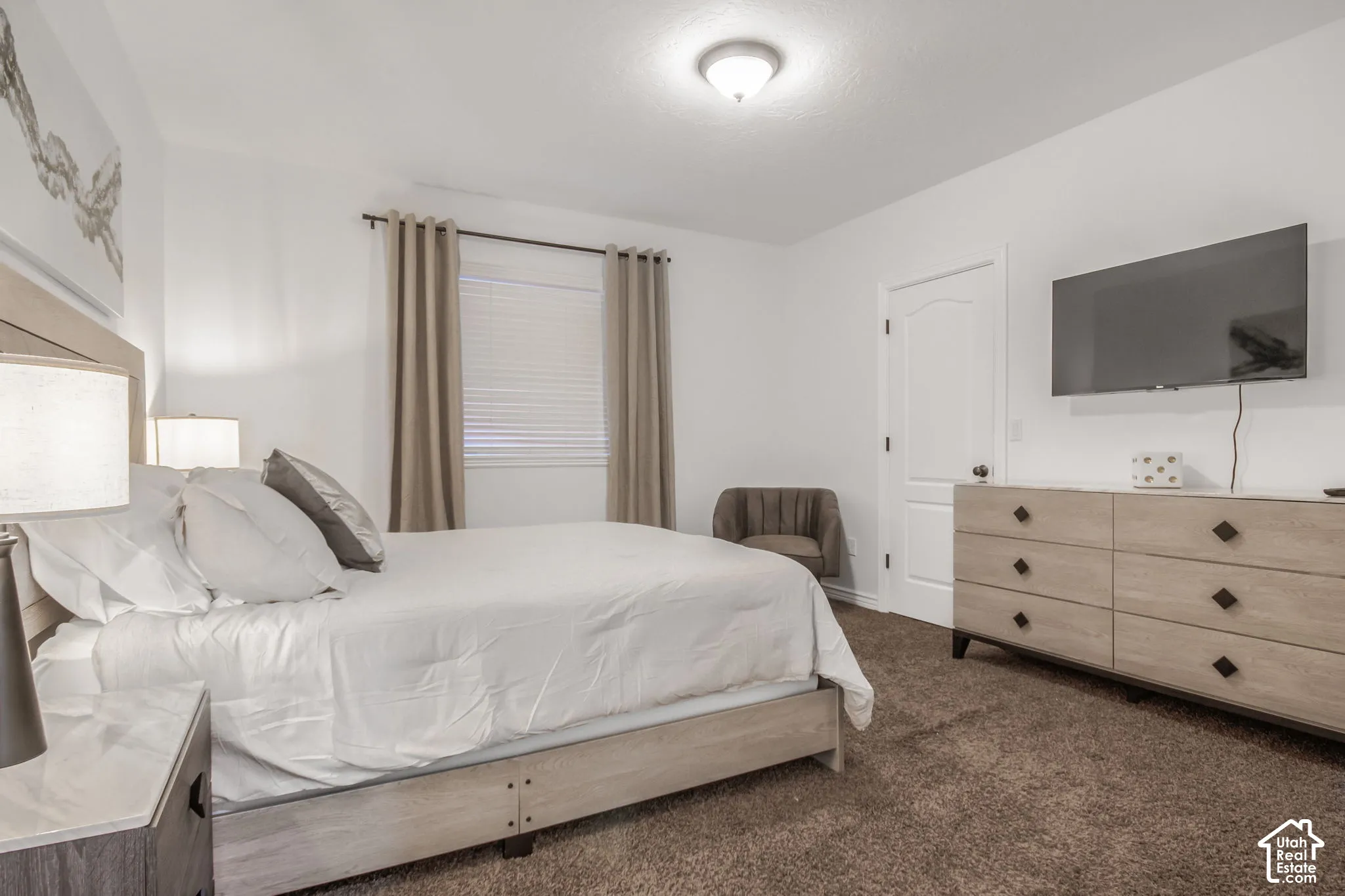 Neutral-toned carpeting, window with neutral window treatments, semi-flush mount ceiling lighting, and arched-top interior door