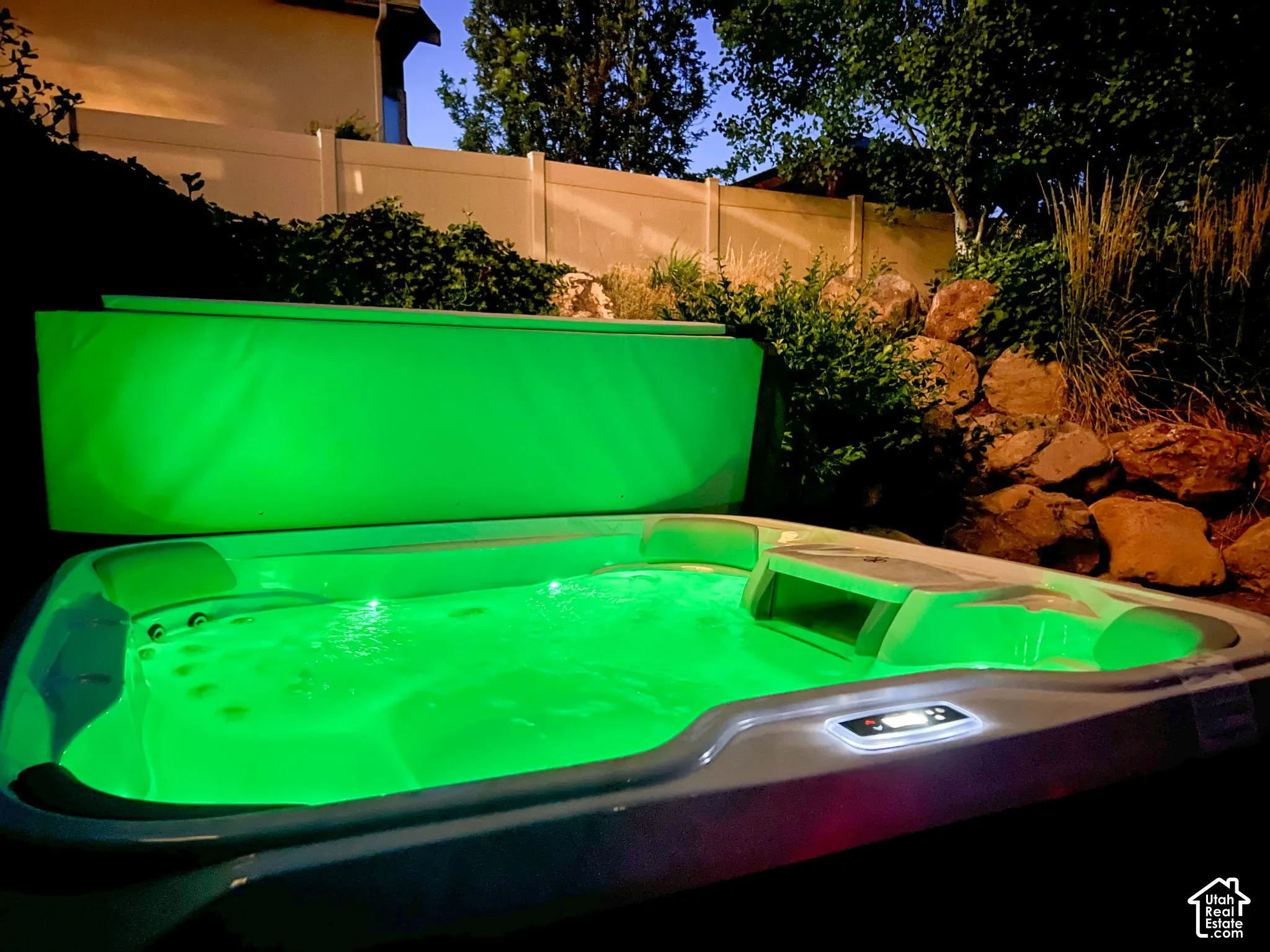 In-ground hot tub featuring built-in jet seating, landscape rock terracing, and privacy fencing