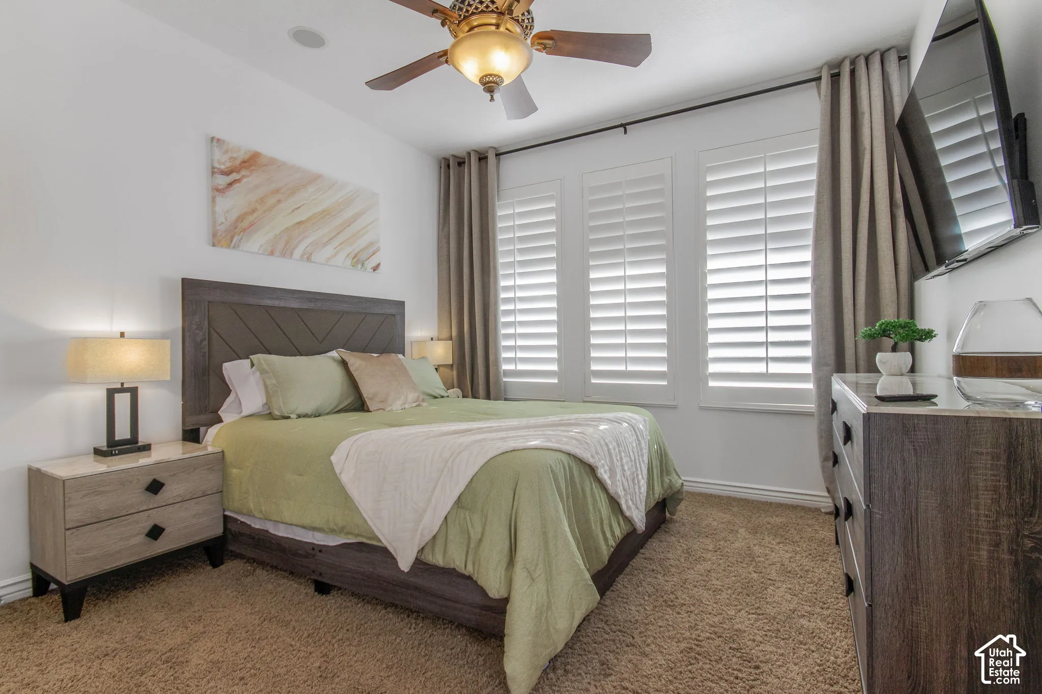 Triple window configuration with white plantation shutters, ceiling fan with integrated lighting, and wall-to-wall carpeting