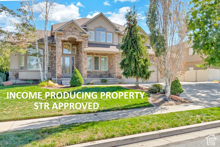 Multi-level exterior featuring stone veneer accents, stucco siding, arched entryway, multi-pane windows, and a paved driveway