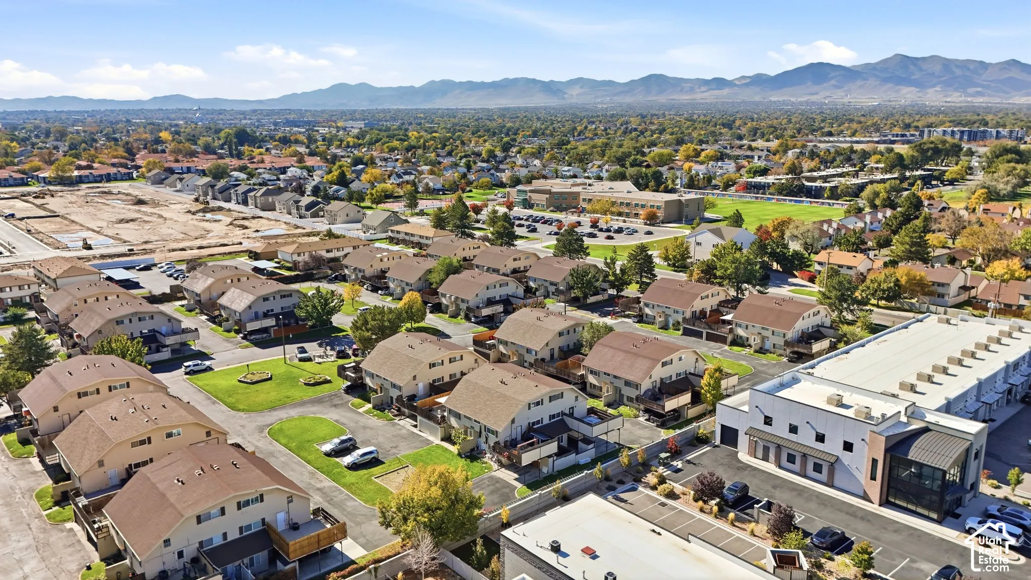 Aerial perspective featuring suburban residential housing, paved parking areas, and a distant mountain range backdrop