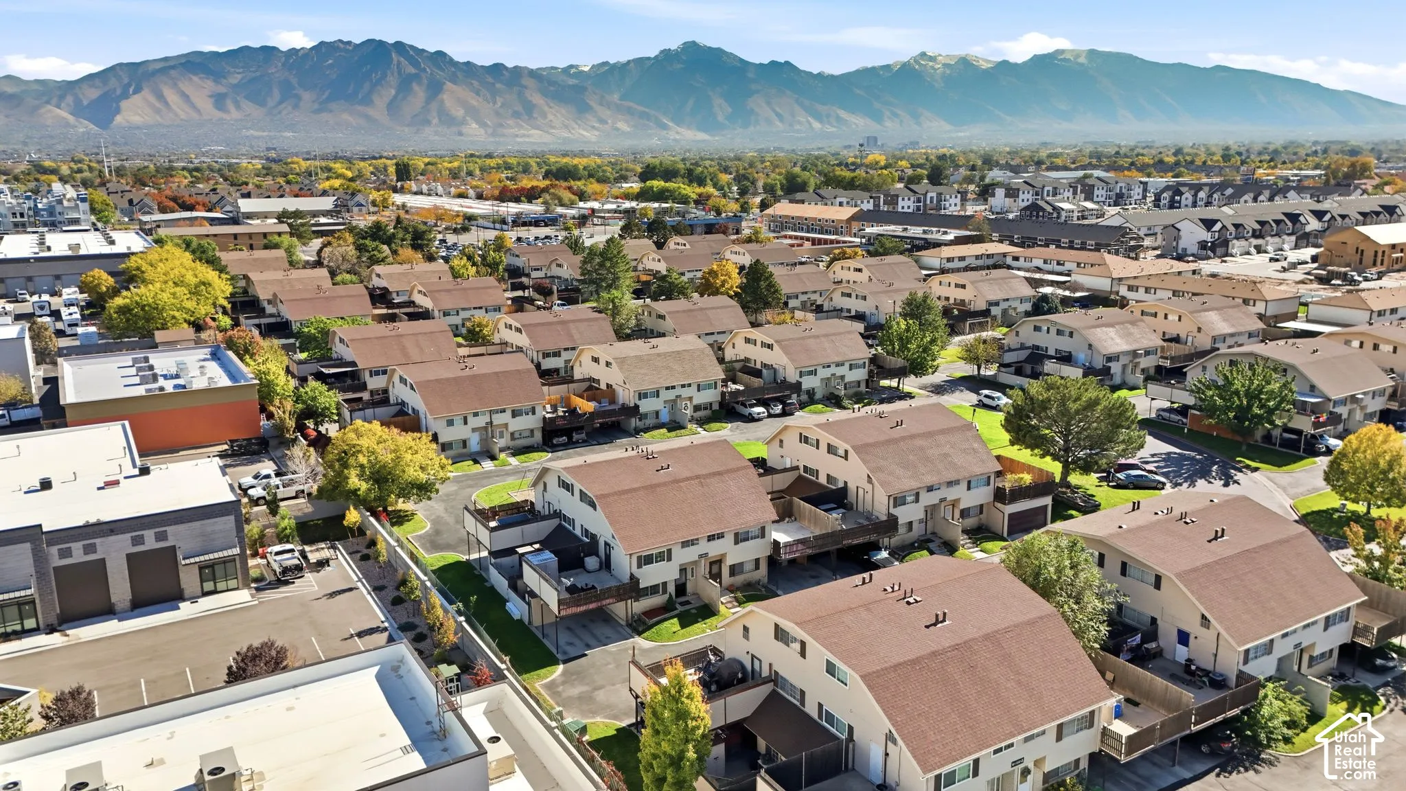 Aerial perspective featuring multi-story residential architecture, shingled roofing, paved surfaces, and prominent mountain scenery