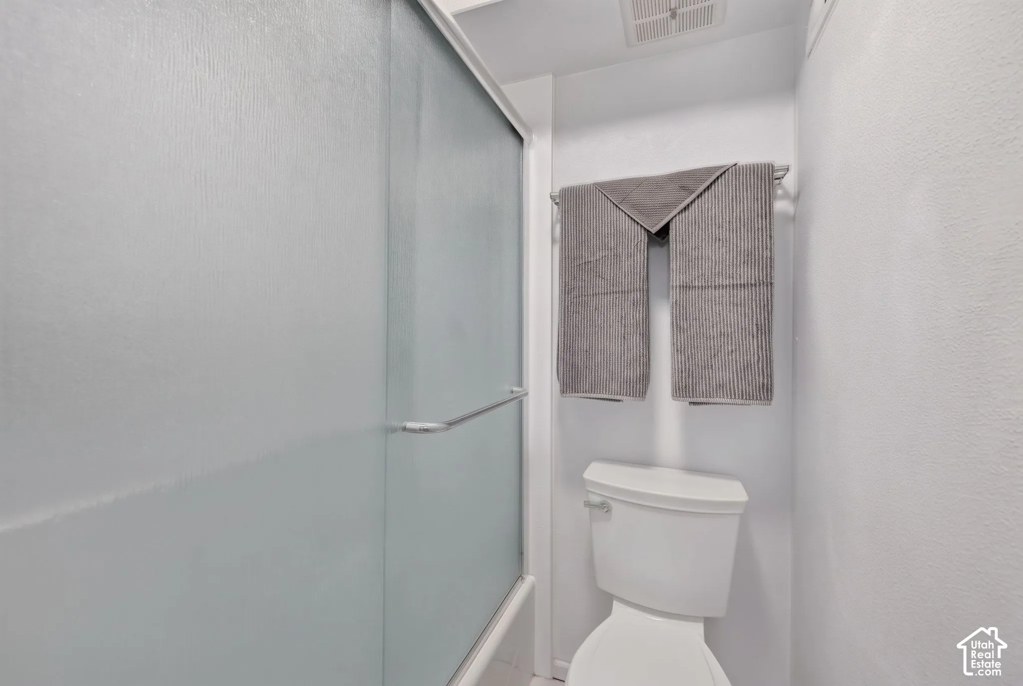 Primary Bathroom tub and shower. Frosted glass sliding shower enclosure with chrome hardware and a standard-height commode