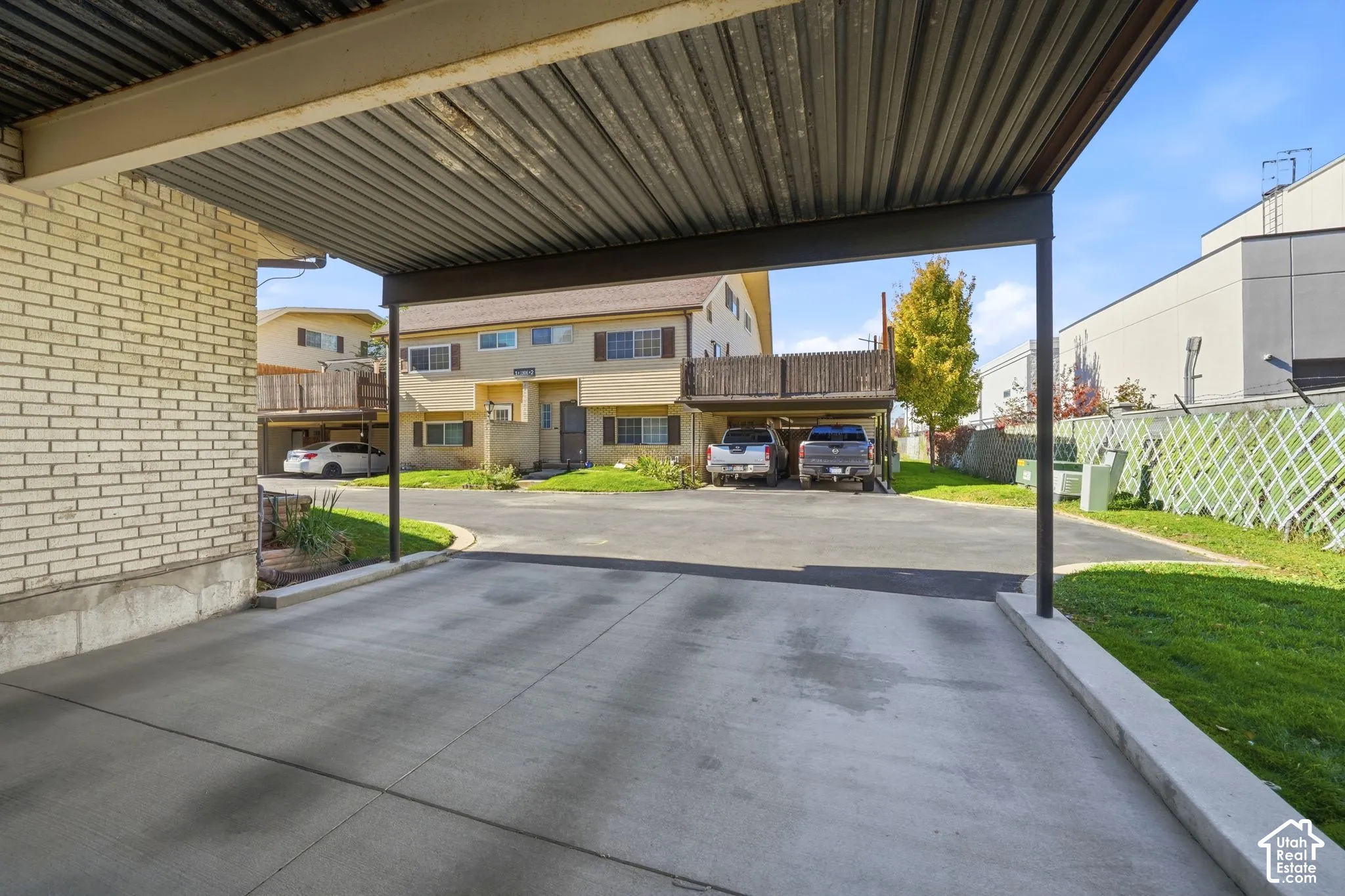 Covered 2 car carport featuring a metal roof, concrete parking pad, and light-colored brick exterior siding