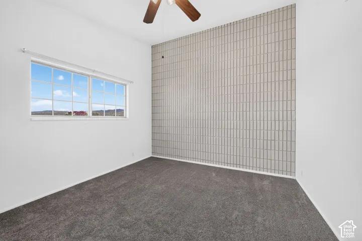 Room featuring a floor-to-ceiling textured tile accent wall, wall-to-wall carpeting, and a multi-pane window with mountain scenery