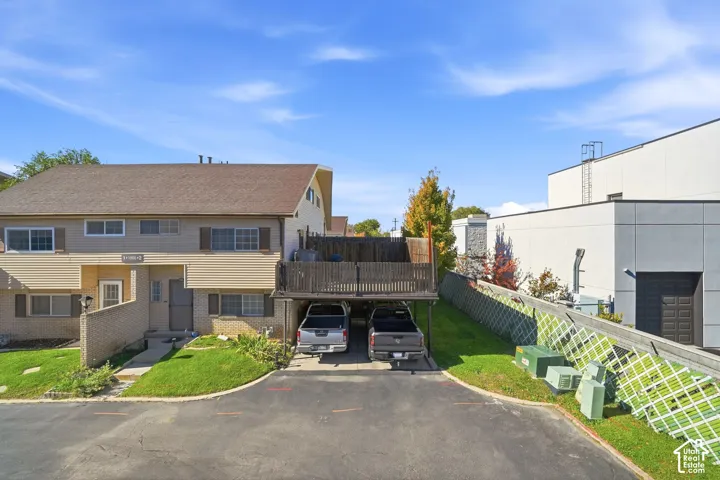 View from the deck. Multi-level residence featuring a covered carport, elevated wood deck with perimeter fencing, asphalt driveway, and shingle roofing