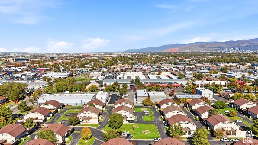 Aerial perspective featuring multi-unit structures with shingled roofing and expansive mountain and city horizon scenery