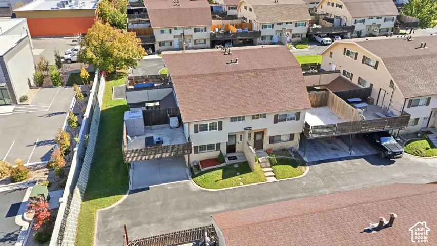 Townhome Row End, Twin home Style Build with Brick Shared Common- Party Wall. Multi-level residence featuring a brown shingle roof, attached elevated decks with wood railing, paved surface parking, and manicured lawn space