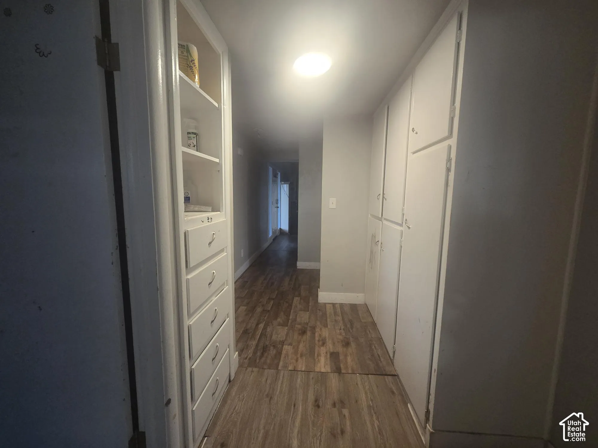 Built-in storage cabinetry with five stacked drawers and open shelving, paired with wood-finish flooring and ceiling-mounted lighting