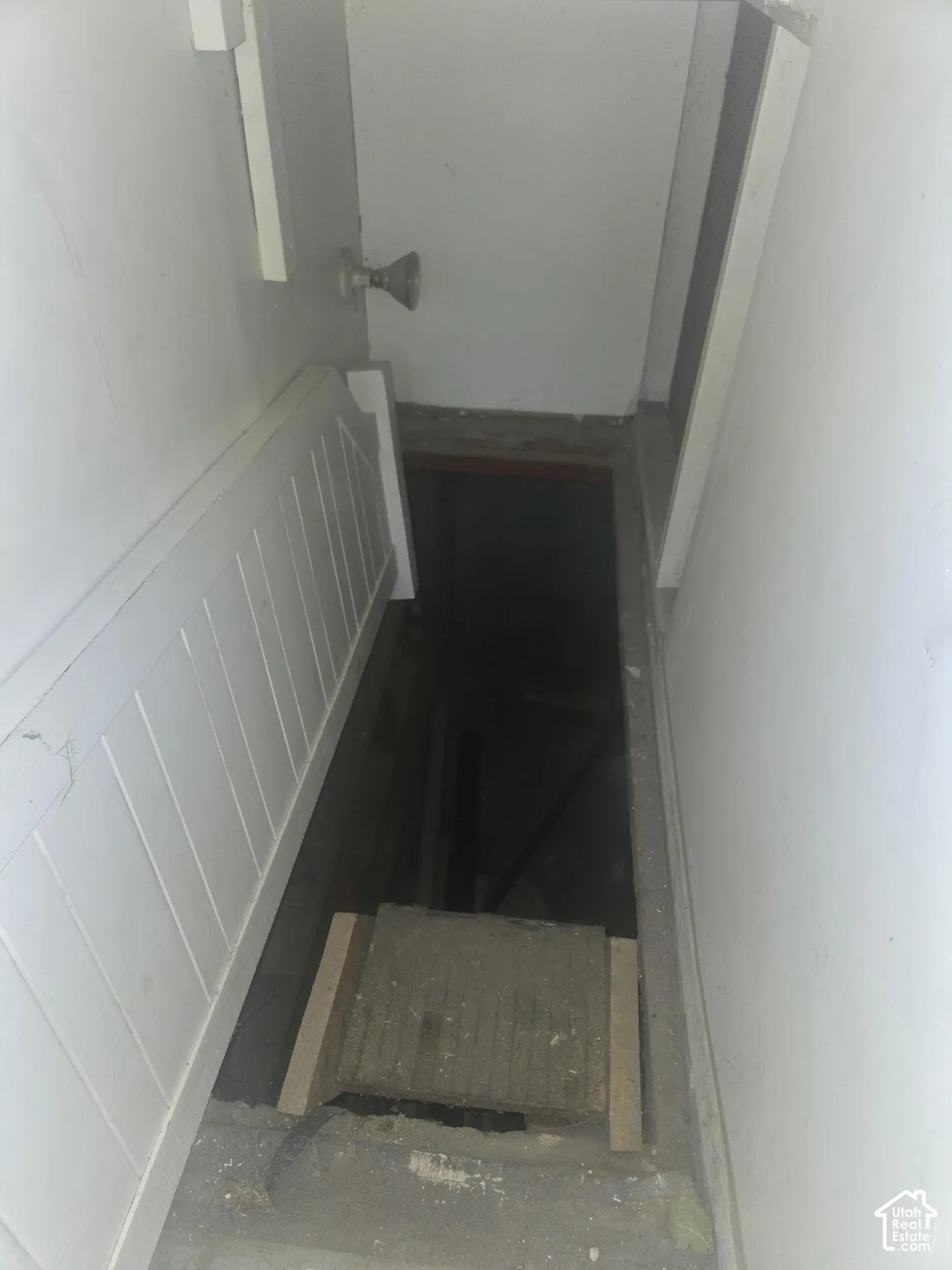 Interior stairwell featuring white paneled wainscoting and a metal door handle