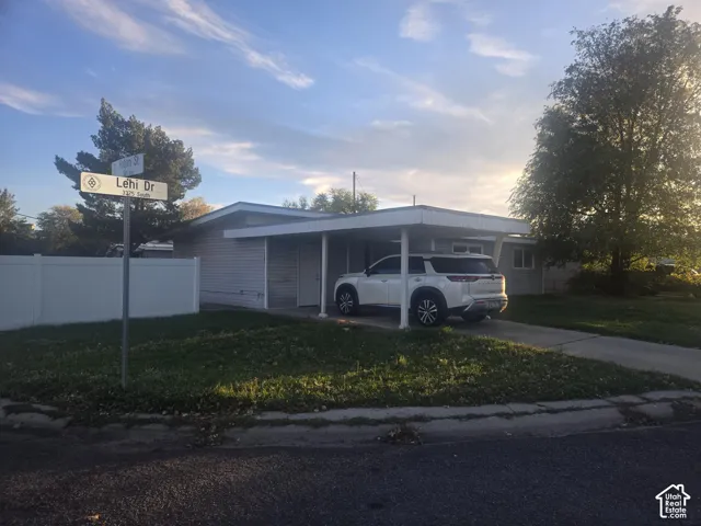 Exterior featuring a covered carport, light-toned horizontal siding, and a white privacy fence