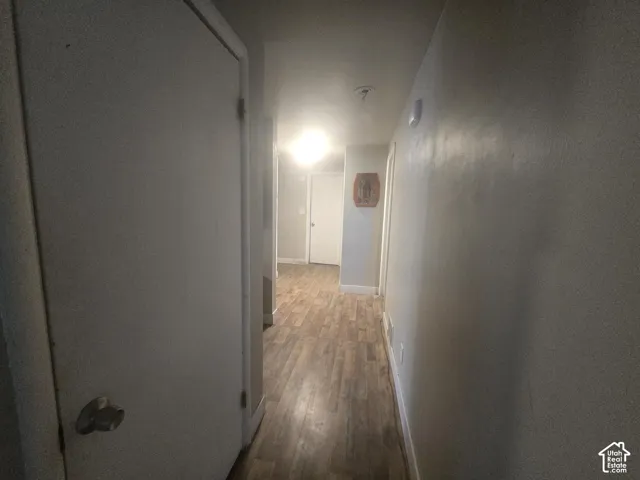 Interior hallway featuring neutral wall paint, wood-finish flooring, and solid-core interior doors with metallic hardware