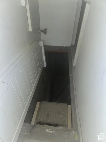 Interior stairwell featuring white paneled wainscoting and a metal door handle
