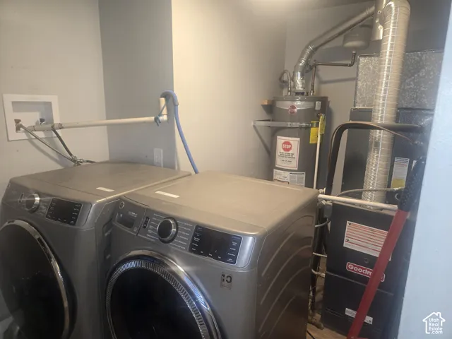 Utility area featuring an integrated water heater, forced-air furnace unit, and recessed laundry hookups