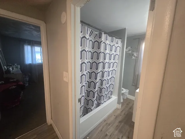 Bathroom featuring wood-finish flooring and a white tub-shower combination