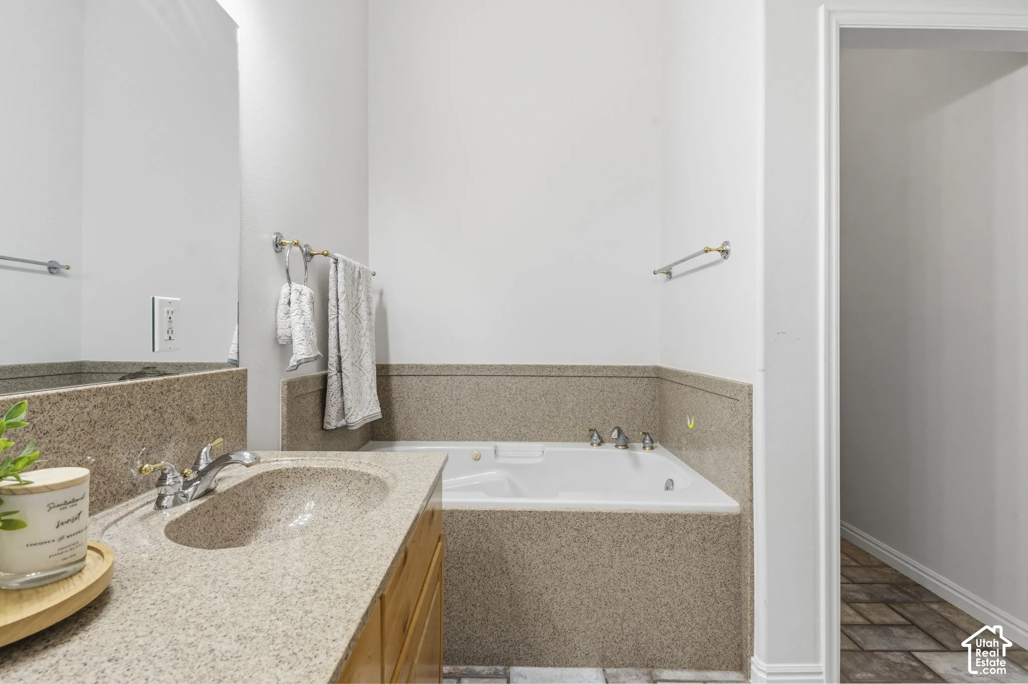 Bathroom featuring a built-in jetted tub with stone-composite surround, integrated vanity countertop with an oval under-mount sink, and a large wall-mounted mirror