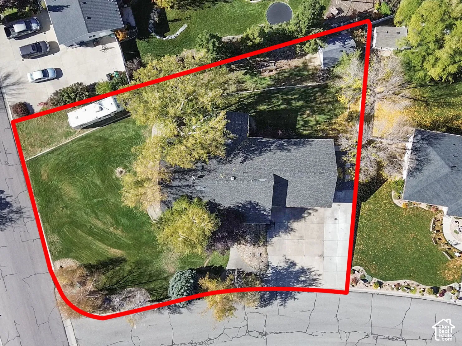 Aerial perspective of a lot featuring an expansive lawn, mature trees, a concrete driveway, and a shingle-roof structure situated on a cul-de-sac