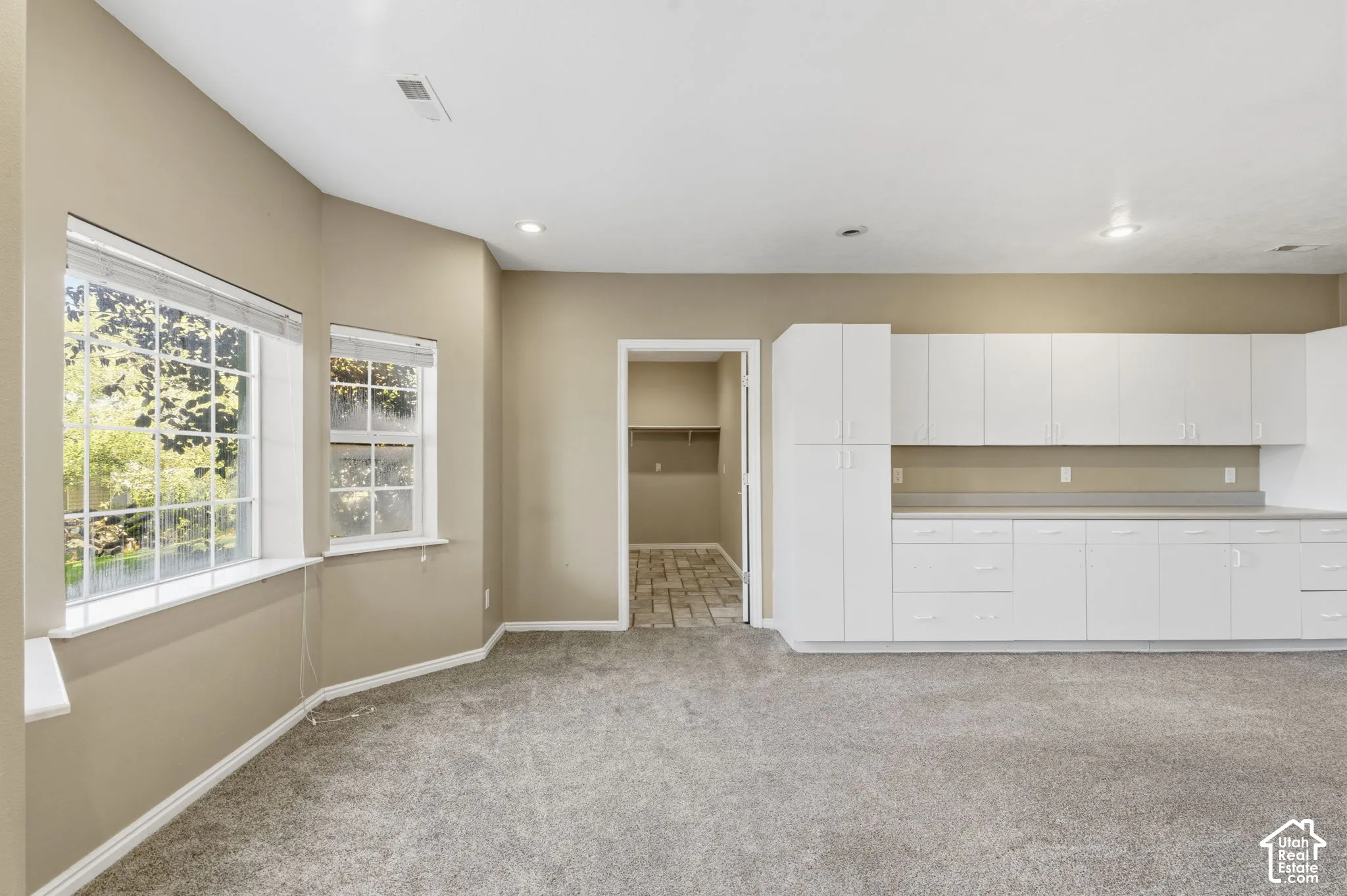 Expansive room featuring wall-to-wall carpeting, recessed lighting, white built-in cabinetry with extensive counter space, and windows with multi-pane glazing