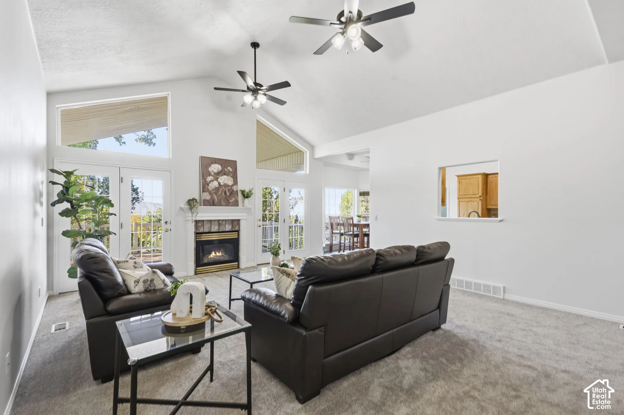 Vaulted ceilings, a stone-surround fireplace with a mantel, multiple glass-paned doors, and clerestory windows