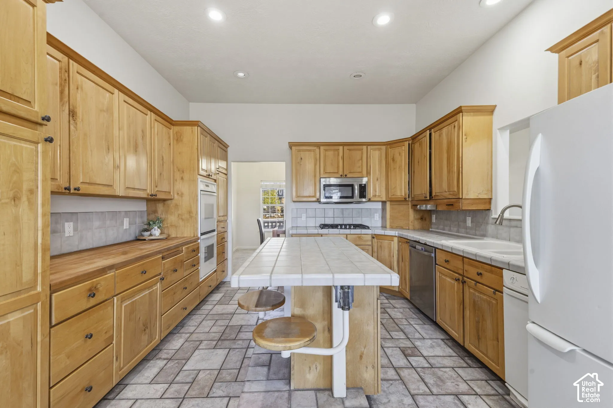 Kitchen featuring natural wood cabinetry, tiled island countertop, tile flooring, built-in double oven, and recessed lighting
